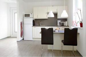 a kitchen with a white refrigerator and two chairs at BerLietz in Berlin