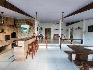 a large kitchen with a brick wall and wooden tables at Recanto Amoreira in São João da Aliança