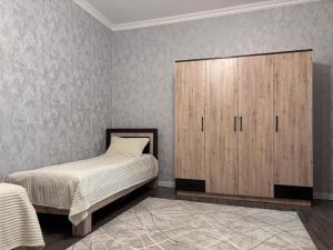 a bedroom with a bed and a wooden cabinet at Shahdag S&R House in Qusar