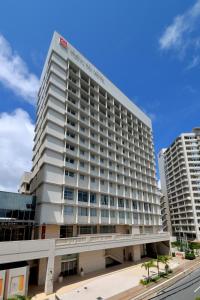 a large white building with two tall buildings at Naha Tokyu REI Hotel in Naha