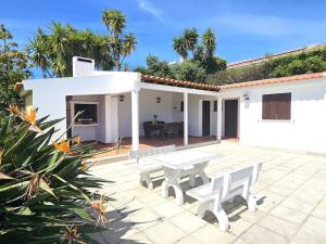 a patio with a table and benches in front of a house at 4 chambres, piscine Casa Oleias by SesimbraSunSea in Sesimbra