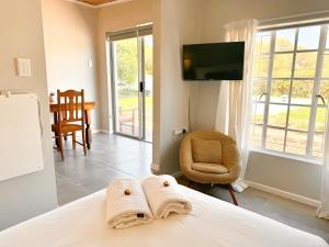 a bedroom with a bed and a tv and a chair at Vrede Villa - no loadshedding in Beaufort West