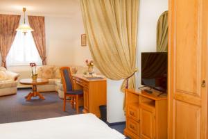 a hotel room with a bed and a desk with a television at Hotel Wesselényi in Győr