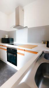 a white kitchen with a sink and a microwave at grand loft avec patio proche des quais Strasbourg in Strasbourg