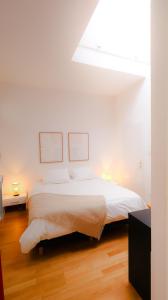 a bedroom with a white bed with two pictures on the wall at grand loft avec patio proche des quais Strasbourg in Strasbourg