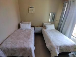 two beds sitting next to each other in a room at 21 Pin Oak Guest House in Cape Town