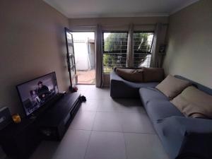 a living room with a couch and a tv at 21 Pin Oak Guest House in Cape Town