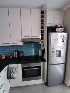 a kitchen with white cabinets and a refrigerator at 21 Pin Oak Guest House in Cape Town