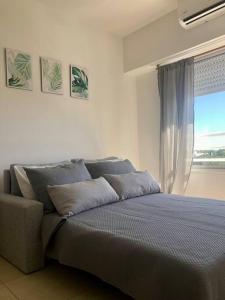 ein Bett in einem Schlafzimmer mit einem Fenster und einem Sofa in der Unterkunft El departamento de Mel in Villa Luzuriaga