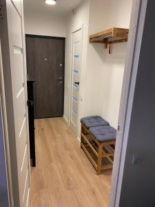 a hallway with a blue ottoman and a door at Reiņu meža Apartaments in Liepāja