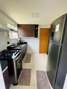 Il comprend une cuisine équipée d'un réfrigérateur en acier inoxydable et d'une cuisinière. dans l'établissement Apartamento 2 quartos completo, à Santa Teresa