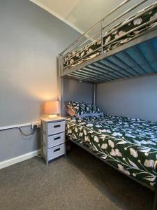 a bedroom with a bunk bed and a night stand at Sandy Paws in Trusthorpe