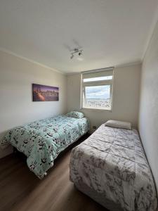 a bedroom with two beds and a window at Departamento nuevo excelente ubicación cómodo y amplió de 1 a 4 personas con estacionamiento in Puerto Montt