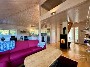 a living room with a purple couch and a fireplace at Cabin at Sjusjøen Birkebeiner trail ski in out, 8 beds, 2 bathrooms & Wifi in Sjusjøen