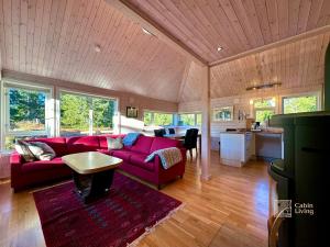 a living room with a red couch and a table at Cabin at Sjusjøen Birkebeiner trail ski in out, 8 beds, 2 bathrooms & Wifi in Sjusjøen