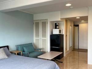 a bedroom with a bed and a couch and a chair at プリンスプラージュ901 in Onna