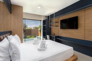 a bedroom with a large white bed with a flat screen tv at Pousada Villas Bonito in Bonito