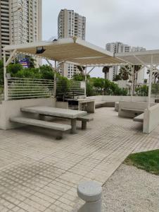 a picnic shelter with benches and an umbrella at Marina 1 piso 23 in Coquimbo