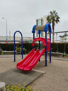 a playground with a red slide in a park at Marina 1 piso 23 in Coquimbo