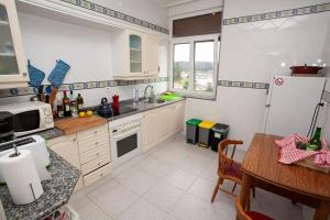 a kitchen with white cabinets and a table and a refrigerator at Sea Breeze and beautiful views! in Muros de Nalón +26 photos