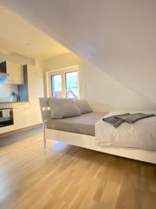 a white bedroom with a bed and a kitchen at Charmantes Studio-Apartment im Herzen von Neureut - Fußbodenheizung, Regendusche, Waschmaschine, Stellplatz in Karlsruhe