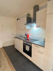 a kitchen with white cabinets and a stove top oven at Charmantes Studio-Apartment im Herzen von Neureut - Fußbodenheizung, Regendusche, Waschmaschine, Stellplatz in Karlsruhe