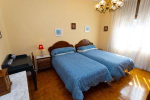 two beds with blue covers in a bedroom at Sea Breeze and beautiful views! in Muros de Nalón