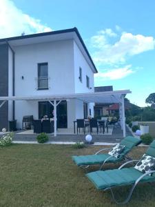 a white house with lawn chairs in the yard at Villa Stella Strandnah in Gryfice