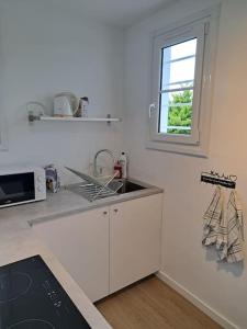a white kitchen with a sink and a window at Maison de bord de mer à Hermanville-sur-mer in Hermanville-sur-Mer +3 photos