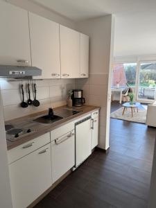 a white kitchen with a sink and a stove at Ferienwohnung Lüttje Mööv an der Nordsee in Wangerland