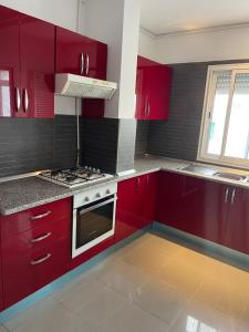 a kitchen with red cabinets and a stove top oven at Deluxe two bedroom apartment with elevator in Ez Zahra