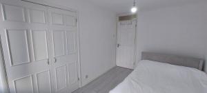 a white bedroom with a bed and a closet at London Travellers Room - Romford, Hornchurch, Gidea Park to Heathrow via Elizabeth line in Harold Wood
