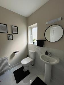 Un baño con inodoro, lavabo y espejo. en Cosy & Comfortable Room, en Portlaoise