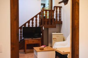 a living room with a staircase with a television at Apartamentos El Pozo 2 in Villanueva de la Vera