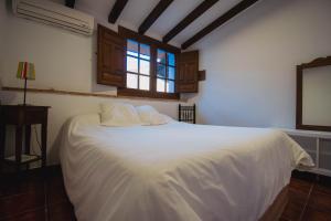 a white bed in a room with a window at Apartamentos El Pozo 2 in Villanueva de la Vera