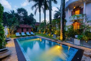 a swimming pool in front of a house with palm trees at Villa 105 in Polgasowita