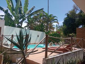 een zwembad met een palmboom naast een hek bij Pousada Caminho da Concha in Itacaré