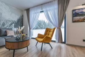 a living room with a couch and a table and a chair at Apartamenty Przełom Białki - plac zabaw, wiata grillowa in Białka Tatrzanska