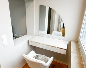 a bathroom with a white chair and a mirror at Elegantes City-Apartment im Herzen von Bad Mergentheim in Bad Mergentheim +5 photos