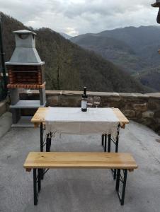 a table with a bottle of wine and a bench at Quirós Villa Tranquila de Salcedo 2 in La Villa