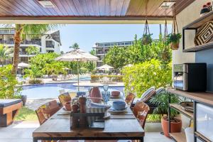 eine Terrasse mit Tisch und Stühlen und einem Pool in der Unterkunft Nannai Residence Muro Alto Porto de Galinhas Beira Mar in Porto De Galinhas