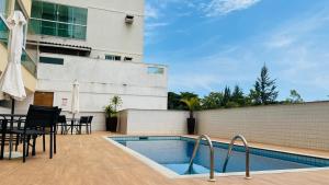 a swimming pool with a table and chairs next to a building at Refúgio Secreto na Praia da Bacutia, Piscina, Churrasqueira, Ar condicionado 80m da melhor praia de Guarapari in Guarapari