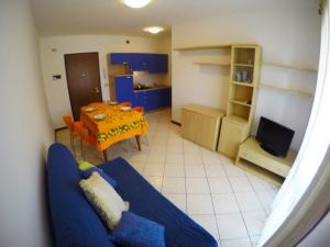 een woonkamer met een blauwe bank en een tafel bij Residence Pineta - Agenzia Cocal in Caorle