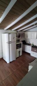 a kitchen with white appliances and a wooden floor at Cabana ferrugem pool in Garopaba