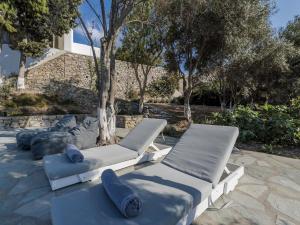 two lounge chairs with blue pillows on a patio at Traditional villa with swimming pool in Ano Mera