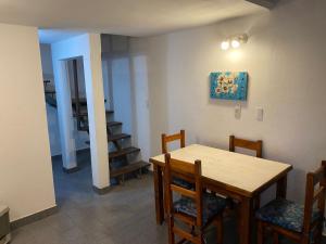 a dining room with a wooden table and chairs at Departamentos El Amanecer in Centenario