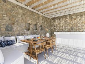 a dining room with a table and a stone wall at Pristine villa with swimming pool in Kalafatis