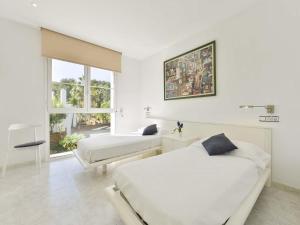 a white bedroom with two beds and a window at Villa in Ibiza with Pool near Cala Bassa Beach in San Antonio +20 photos