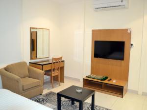 a living room with a couch and a chair and a television at اجنحة النرجس الفندقية in Al Khobar