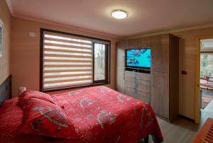 Un dormitorio con una cama roja y un televisor. en Mirabosque New Apartments 3, en Osorno